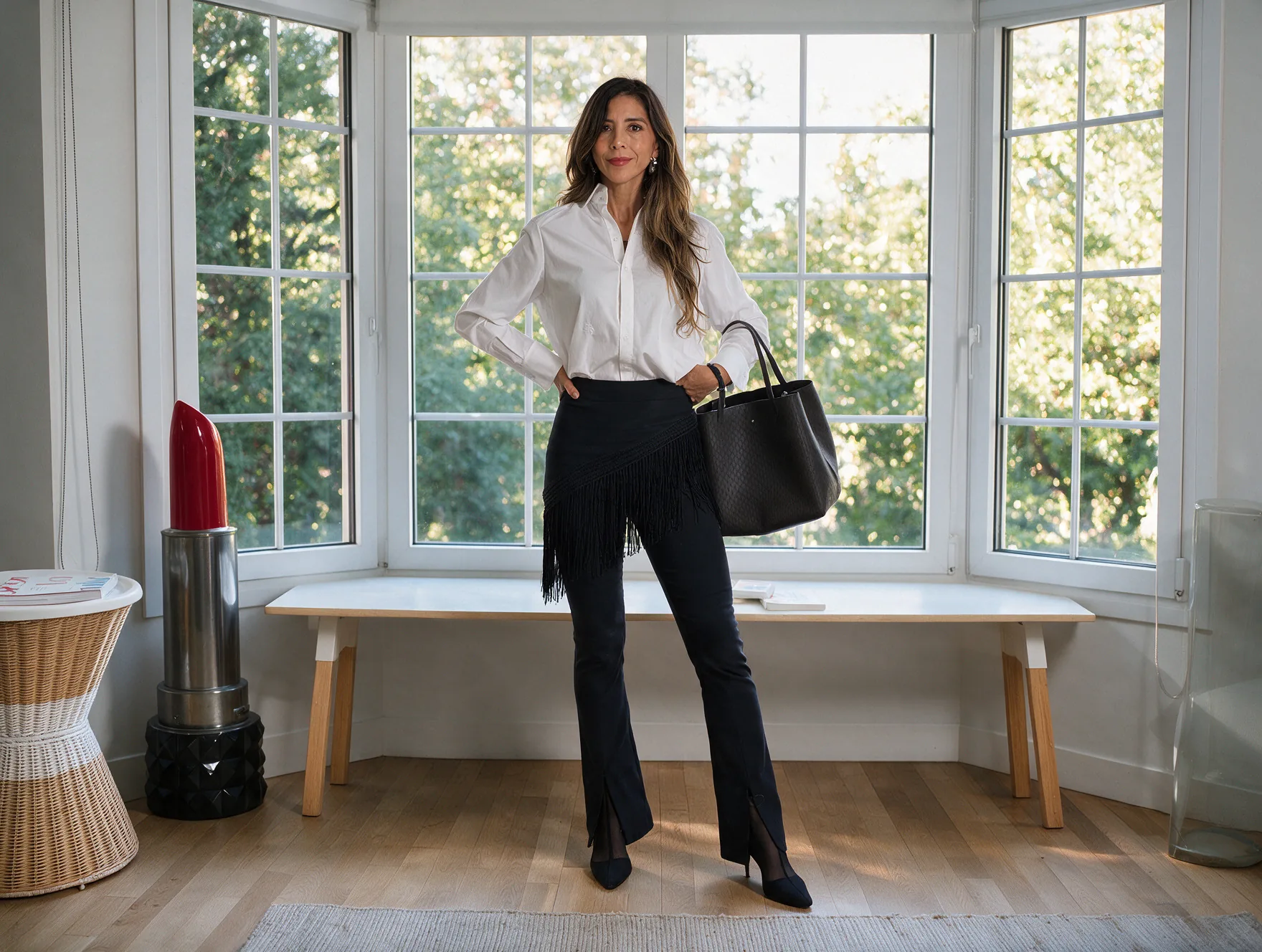 Daniela Peñaloza en estilo dramático: camisa blanca, pantalón negro con aberturas, pañuelo de flecos anudado en diagonal a la cadera, salones negros y bolso grande negro
